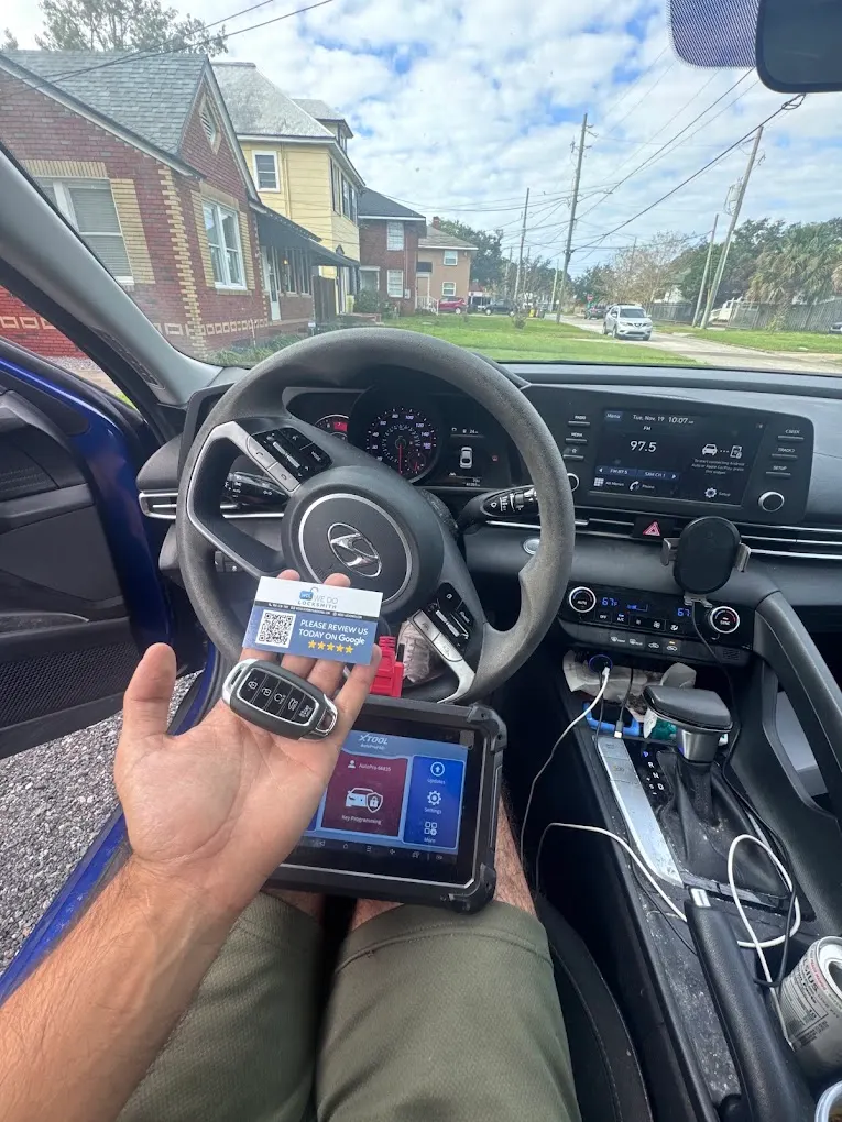Technician holding a new smart key beside a programmer in a customer's car